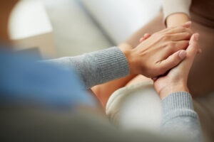 Two people holding hands in support, symbolizing sponsorship and recovery guidance in OA HOW.